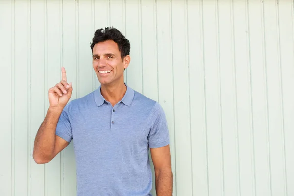 Smiling man pointing one finger — Stock Photo, Image