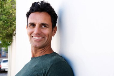 duvara yaslanmış ve kameraya gülümseyen bir adam