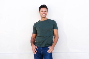 Beyaz duvara yaslanmış ve gülümseyen bir adam