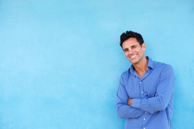 gülümseyen adam mavi duvara yaslanmış
