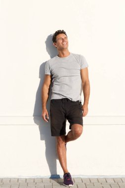adam beyaz duvara yaslanmış şort 