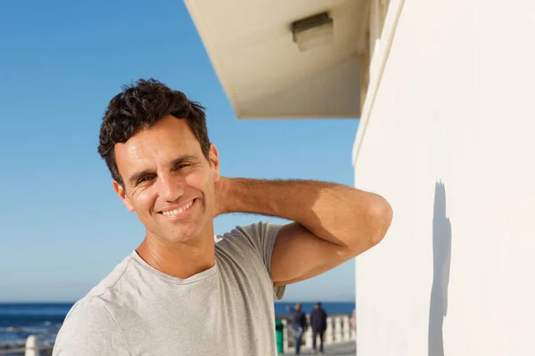 Mann lächelt draußen mit der Hand im Haar — Stockfoto