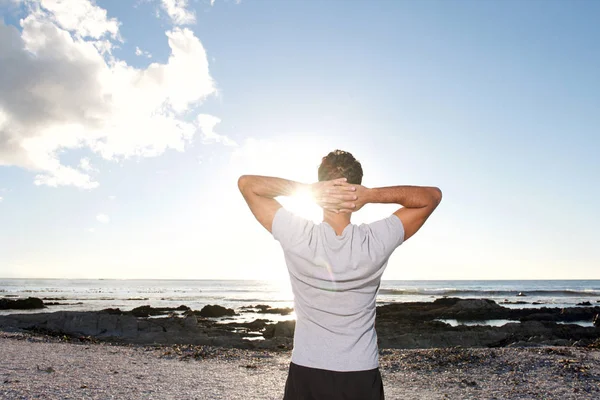 Homme regardant la mer avec les mains derrière la tête — Photo