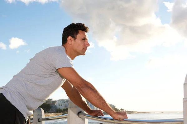 Hombre apoyado en la barandilla exterior y mirando al mar —  Fotos de Stock
