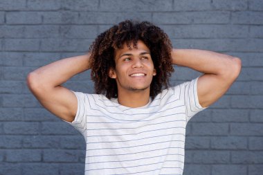 Elleri başının arkasında olan adam.