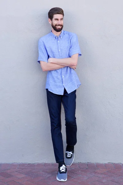 smiling man leaning on wall