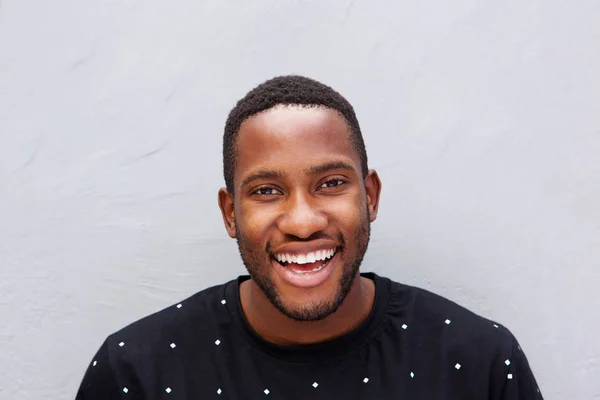 Hombre sonriendo contra la pared gris —  Fotos de Stock