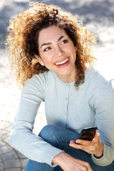 Glückliche junge Frau sitzt draußen — Stockfoto