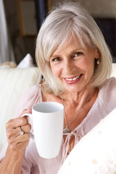 Женщина улыбается с чашкой кофе — стоковое фото
