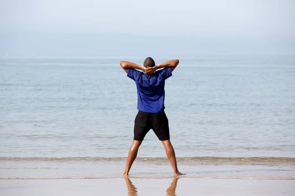 Fitness-Mann steht am Strand — Stockfoto