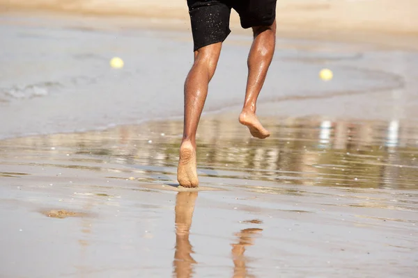 Homem correndo descalço na praia — Fotografia de Stock