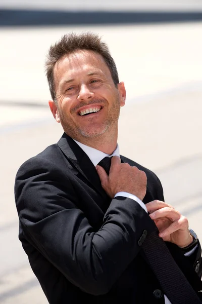 Uomo d'affari sorridente seduto aggiustare cravatta — Foto Stock
