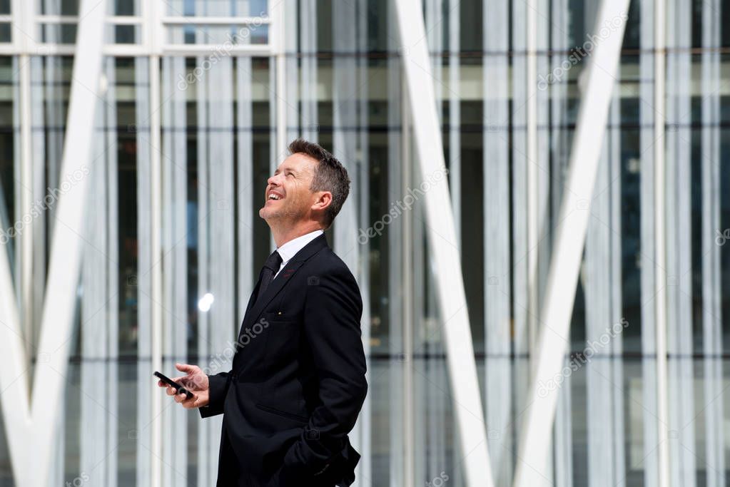 businessman laughing and holding phone