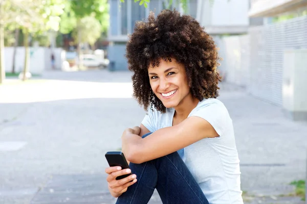 Femme souriante assise à l'extérieur — Photo