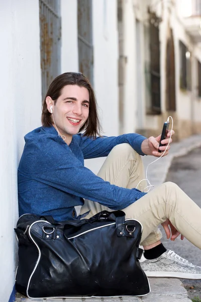 Счастливый человек сидит на городской улице — стоковое фото