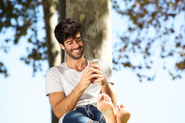 Uomo sorridente seduto accanto all'albero — Foto Stock