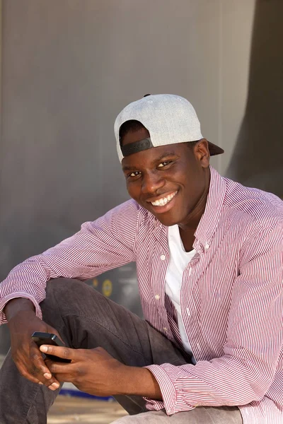 Retrato Del Hombre Africano Sonriente Con Gorra Sentado Con Teléfono —  Fotos de Stock