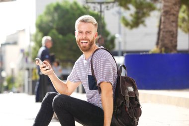 Hareket eden telefon ile dışarıda neşeli genç adam portresi