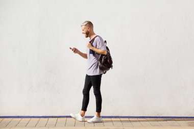 Cep telefonu ile yürüyen yakışıklı genç adam tam uzunlukta portresi