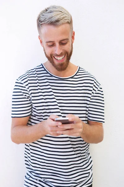 Portrait of smiling young man against white background looking at cell phone