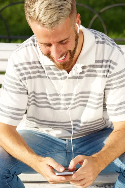 Portrait Smiling Young Man Sitting Smart Phone Earphones — Stock Photo, Image