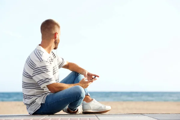 Portret Van Jonge Man Zit Aan Het Strand Met Slimme — Stockfoto