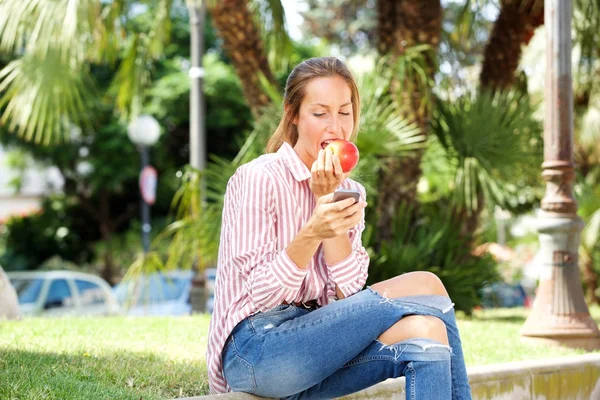 Πορτρέτο Του Υγιούς Νεαρή Γυναίκα Κοιτάζοντας Κινητό Τηλέφωνο Και Τρώει — Φωτογραφία Αρχείου