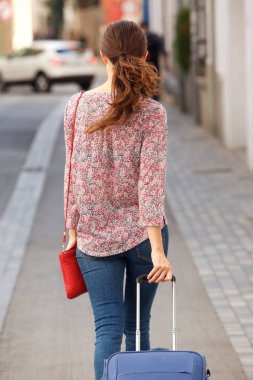 Arka görünüm portre kadın seyahat çantası ile sokakta yürürken