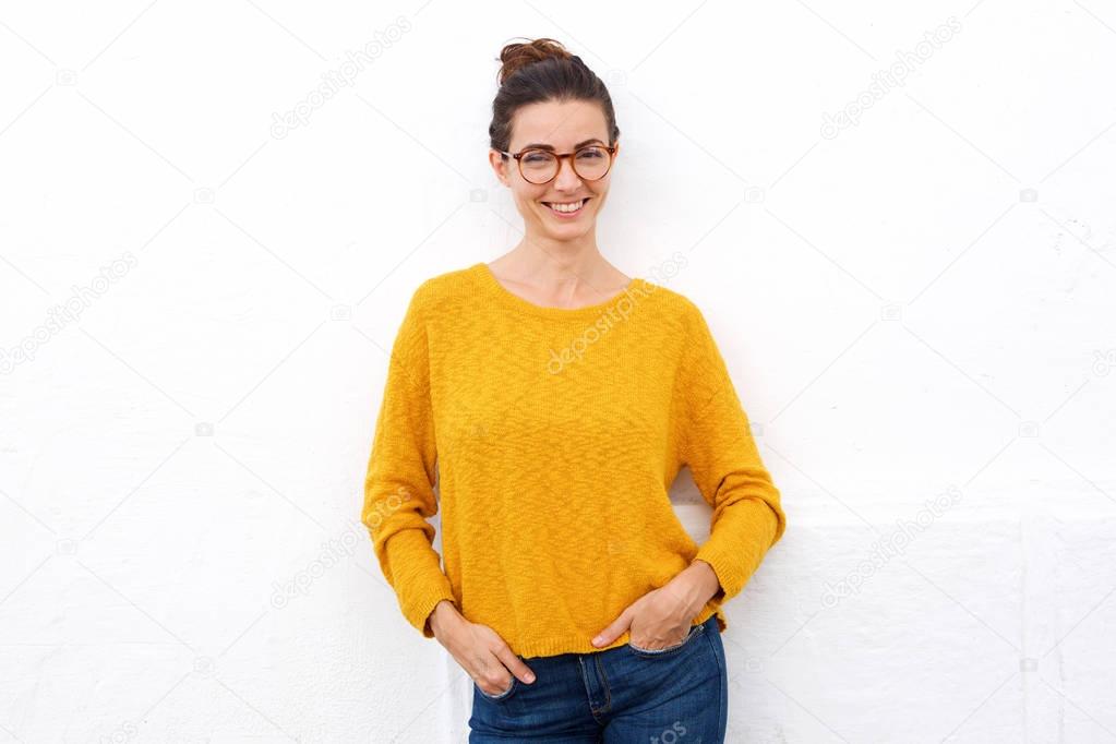 Portrait of attractive young woman smiling with glasses against white wall