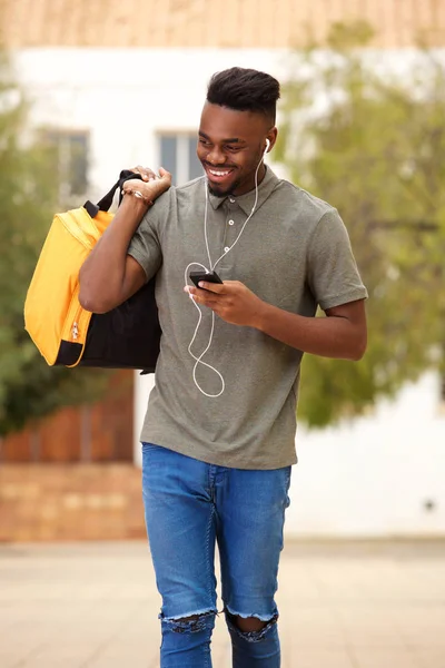 一个很酷的年轻人用手机走路和听音乐用耳机的肖像 — 图库照片