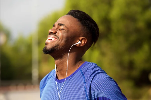 公園でイヤホンと笑って幸せな若い黒人男性の肖像画 — ストック写真