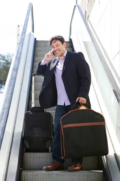 バッグと一緒に旅行 エスカレーターで携帯電話で話している実業家の肖像画 — ストック写真