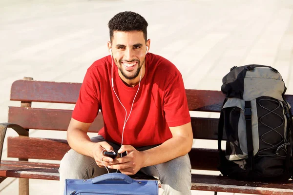 Portret Van Gelukkige Jonge Man Zitten Met Bagage Luisteren Naar — Stockfoto