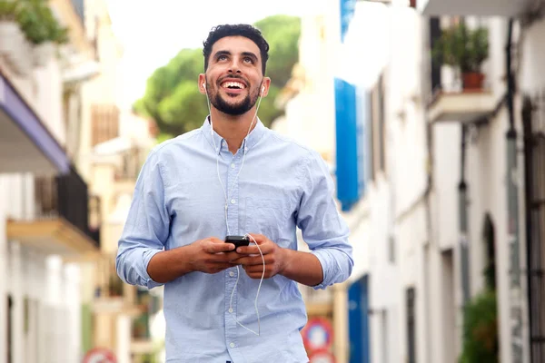 携帯電話 市内のイヤホンと笑って幸せな若いアラビア語男の肖像 — ストック写真