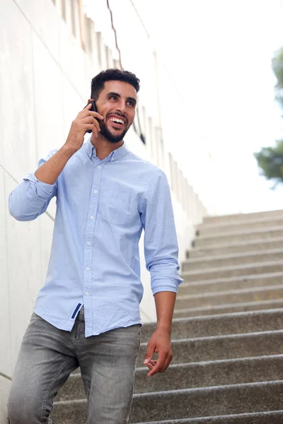Portrait of smiling North African man walking and talking on cellphone