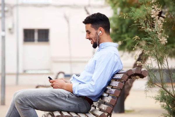 Портрет Североафриканца Сидящего Скамейке Смотрящего Мобильный Телефон Слушая Музыку — стоковое фото