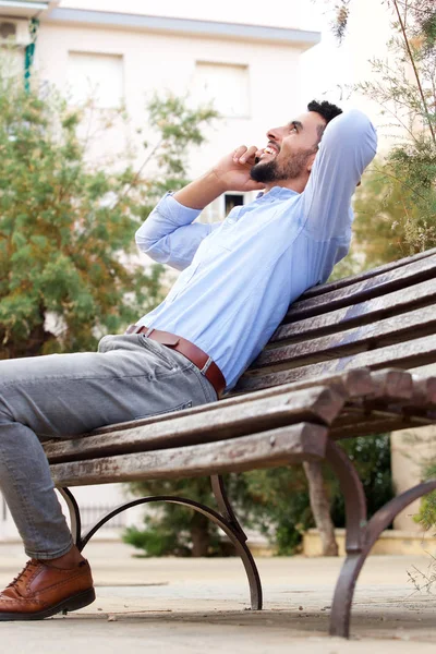 Portrait Young Man Sitting Bench Smiling While Talking Mobile Phone — Stock Photo, Image