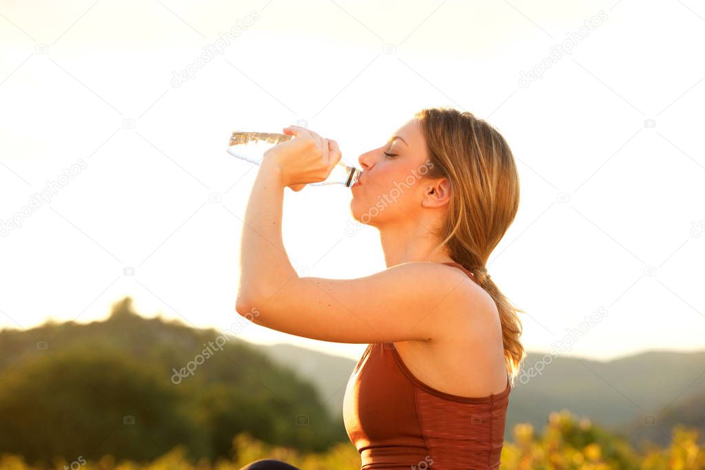Portrait of beautiful young sports woman drinking water outside