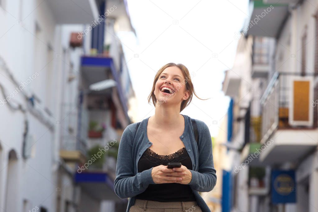 Portrait of attractive young woman laughing with smartphone in the city
