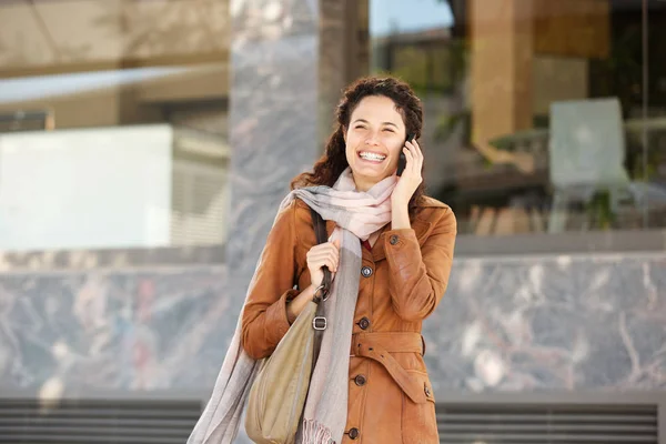 Portrait of happy woman with jacket and scarf talking with smartphone