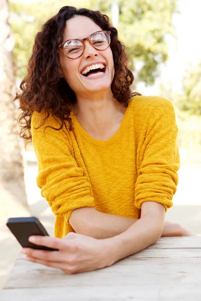 Portrait of happy woman with glasses holding smartphone