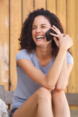 Smartphone üzerinde konuşan ve gülen genç kadın portresi