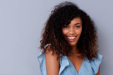 Gri duvara gülümseyen güzel genç Afro-Amerikan kadın portresi kapatın