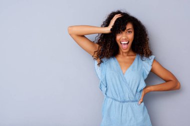 Gri duvara gülüyor neşeli genç Afro-Amerikan kadın portresi