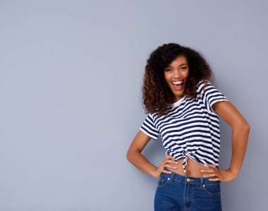 Gri duvara gülümseyen güzel genç Afro-Amerikan kadın portresi