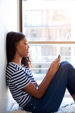 Hareket eden telefon ile oturan genç siyah kadın portresi