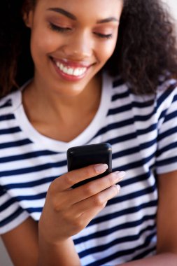 Gülümseyen ve cep telefonu arayan genç bir kadın portresi kapatın