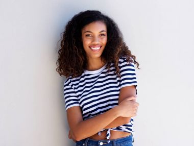 Portrait of confident young black woman smiling against white wall