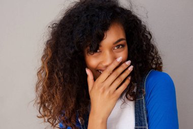 Mutlu genç Afro-Amerikan kadın gri duvara kıkırdayarak portresi