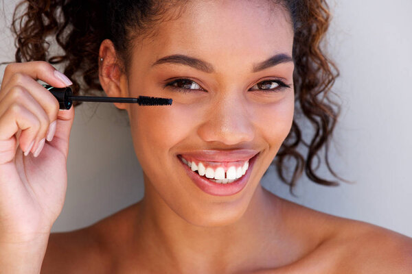 Close up portrait of beautiful young african american woman putting on mascara 